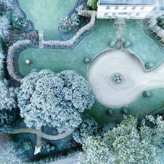 The Old Rectory. House and garden aerial showing the driveway and front lawn seperated from the croquet lawn by pleached hornbeam hedges. Winter. Doynton, South Gloucestershire, UK.